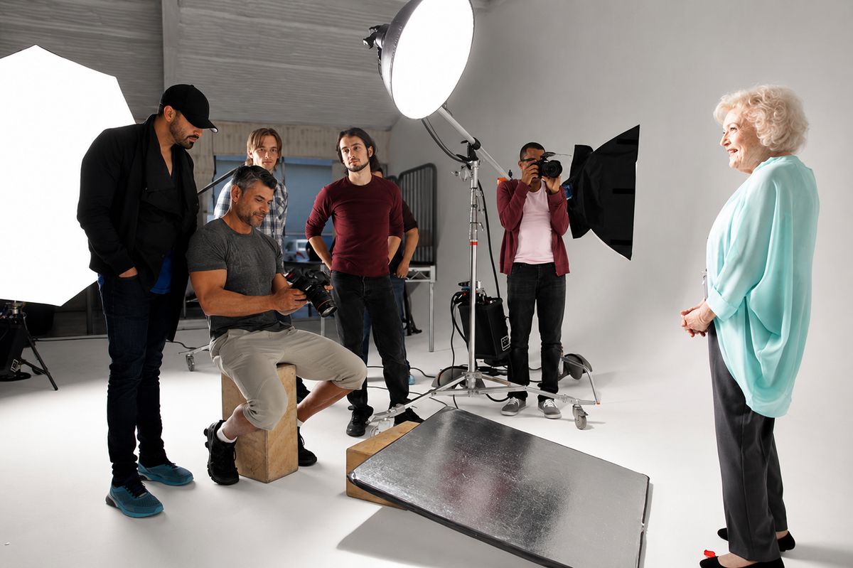 A marketing shoot in progress — full crew, strobes, reflector and grip stands set, with Betty White waiting on her mark